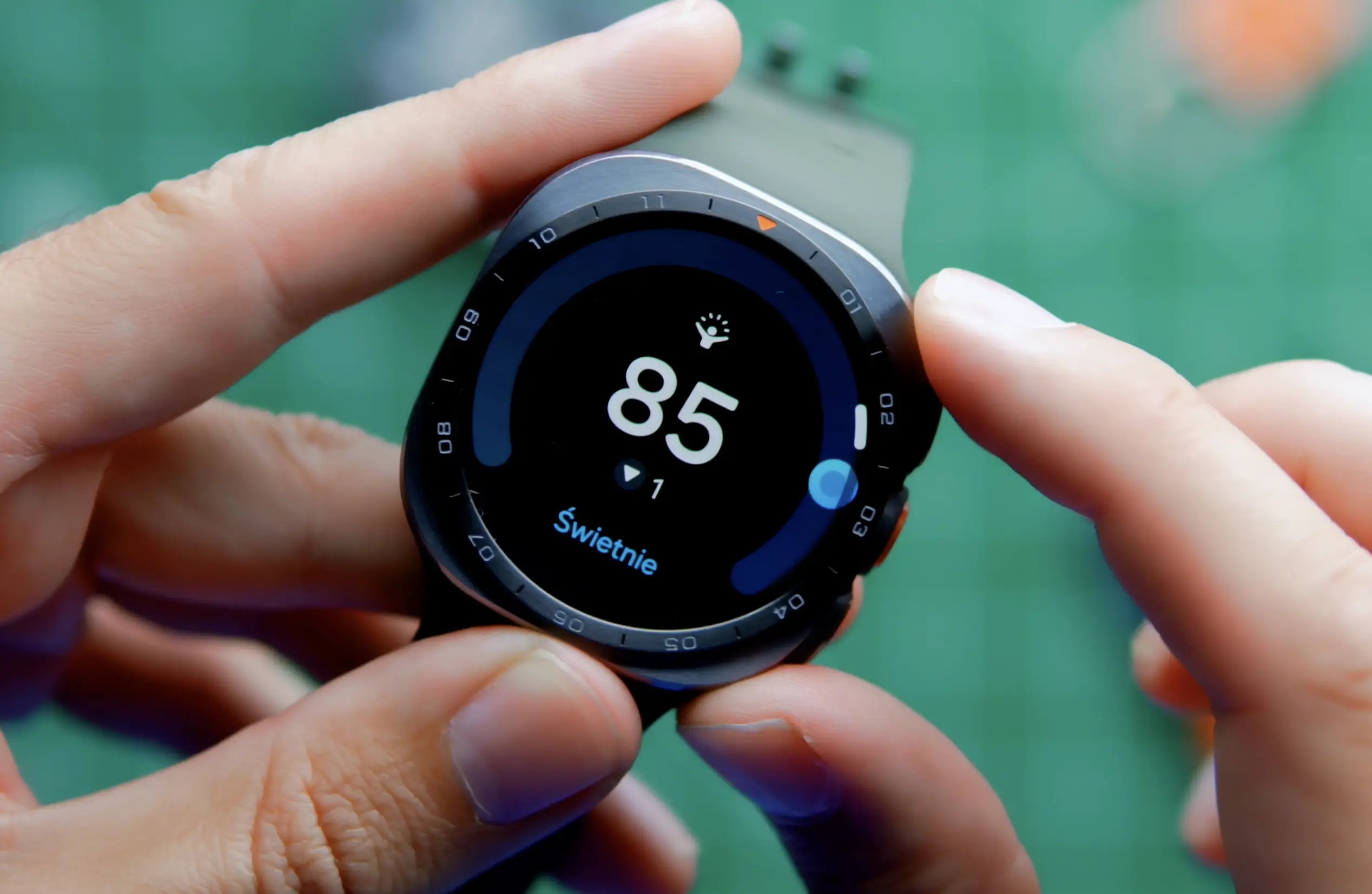 Wyświetlacz zegarka Samsung pokazujący podsumowanie poziomu energii Galaxy AI oraz wskaźniki zdrowotne.