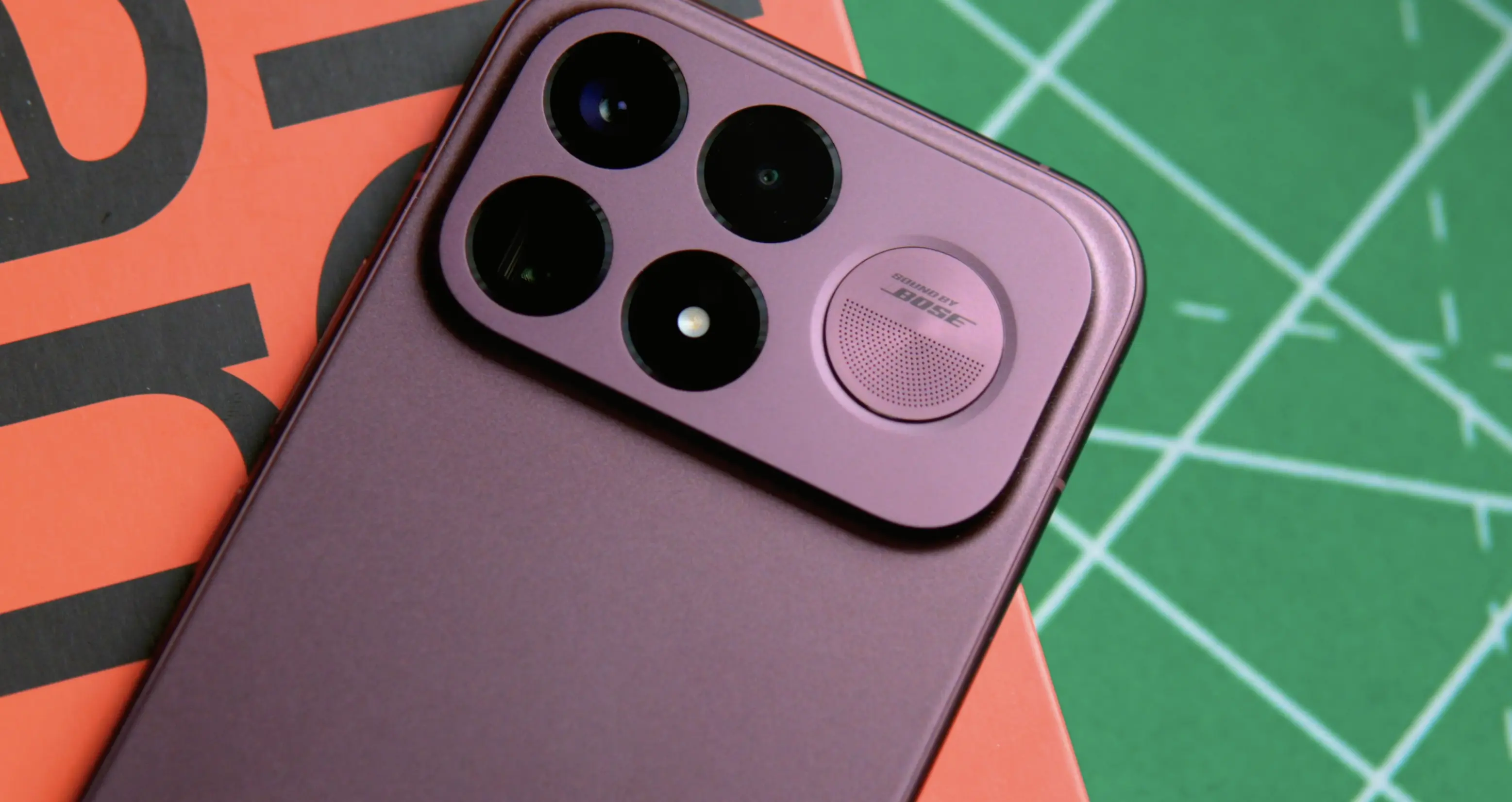 Smartfon POCO F9 Ultra w burgundowym kolorze obudowy z aluminiową wyspą aparatów na biurku.