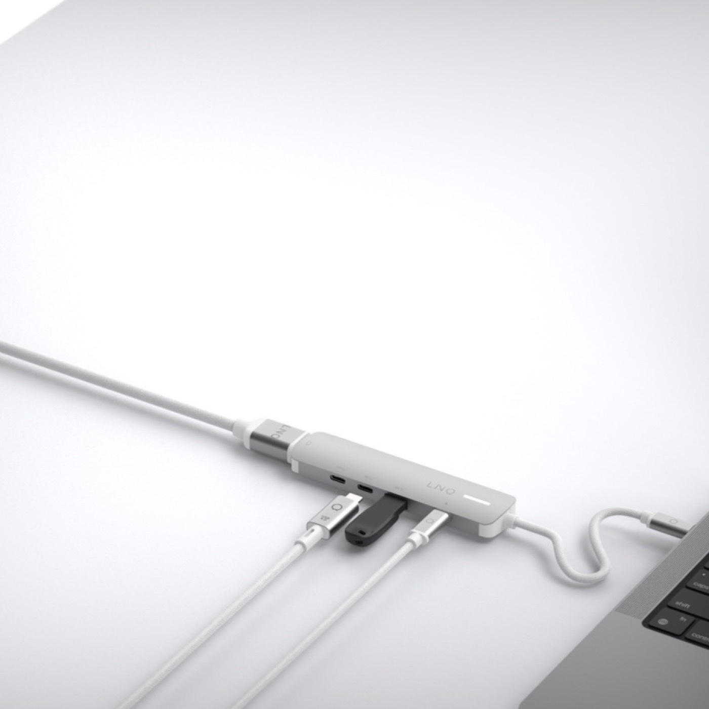 Kompaktowy hub USB-C LINQ 5in1 Pro podłączony do laptopa z kilkoma akcesoriami